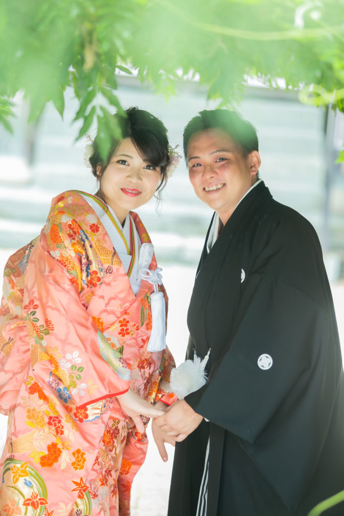 赤い打掛を着た新婦と黒い紋付袴を着た新郎がこちらを振り向いている