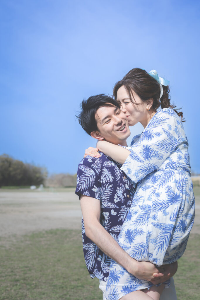 アロハシャツを着たフォトウェディングで新郎が新婦を抱き上げている